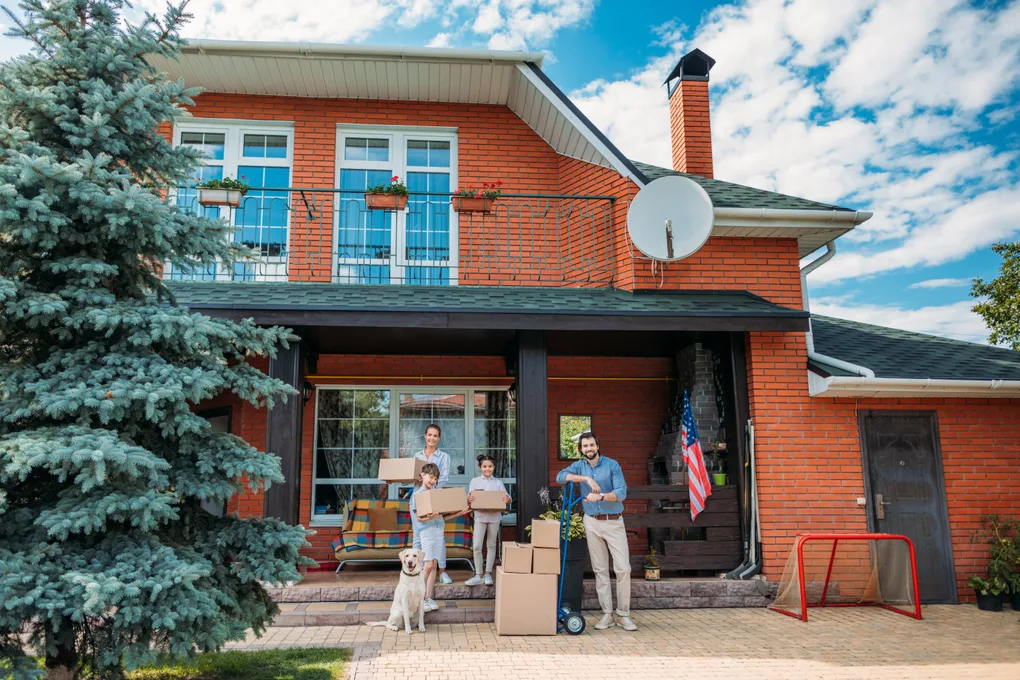 Family unloading moving boxes on the front porch of their new home